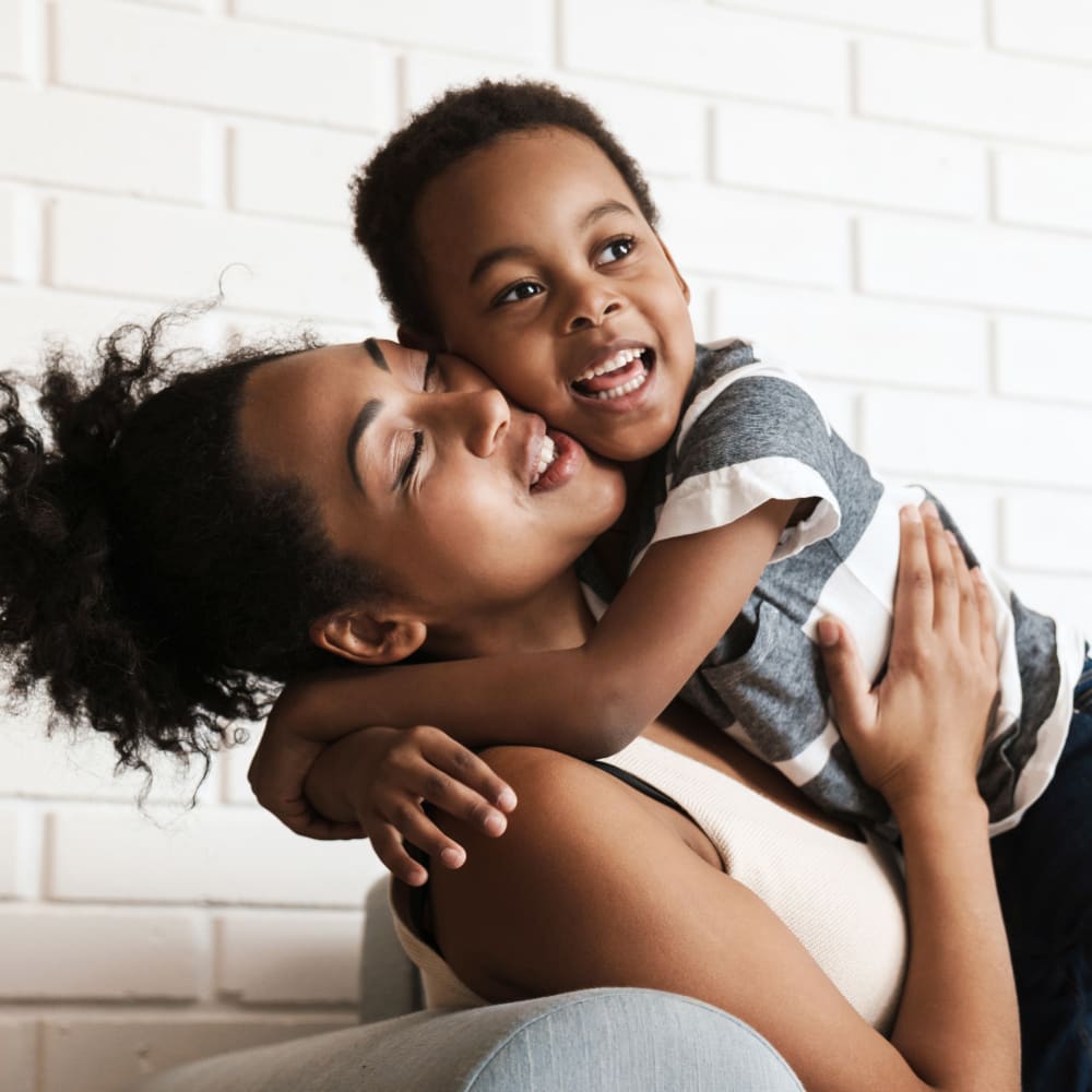 Mom hugging her little son and both are smiling at a visit to Village Orthodontics