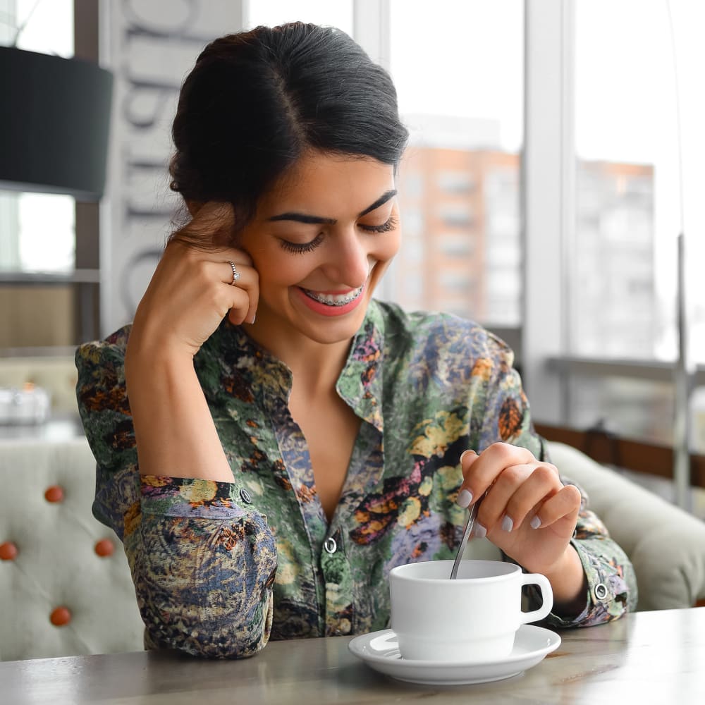 A beautiful girl with dental braces for adults sitting in a coffee shop and smiling