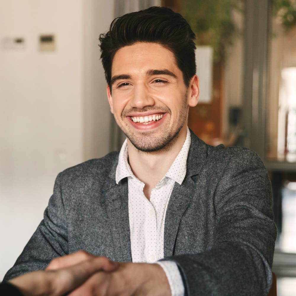 An adult male smiling and shaking hands with the orthodontist at a visit to Village Orthodontics