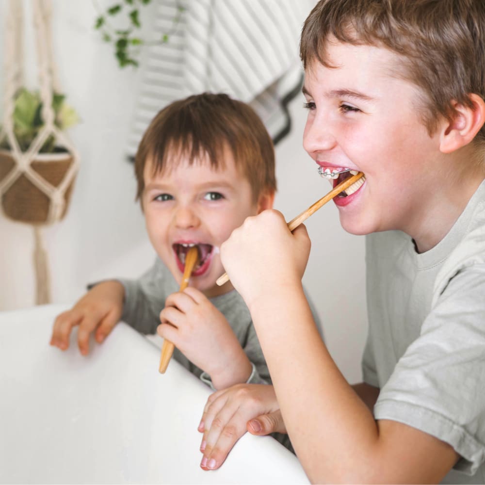 2 boys washing their teeth and having child braces