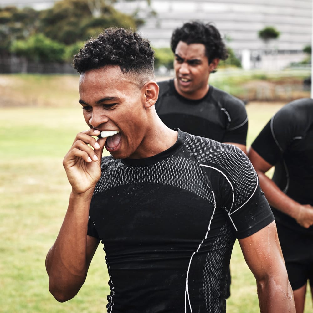 a rugby player puts on his Sports Mouthguards