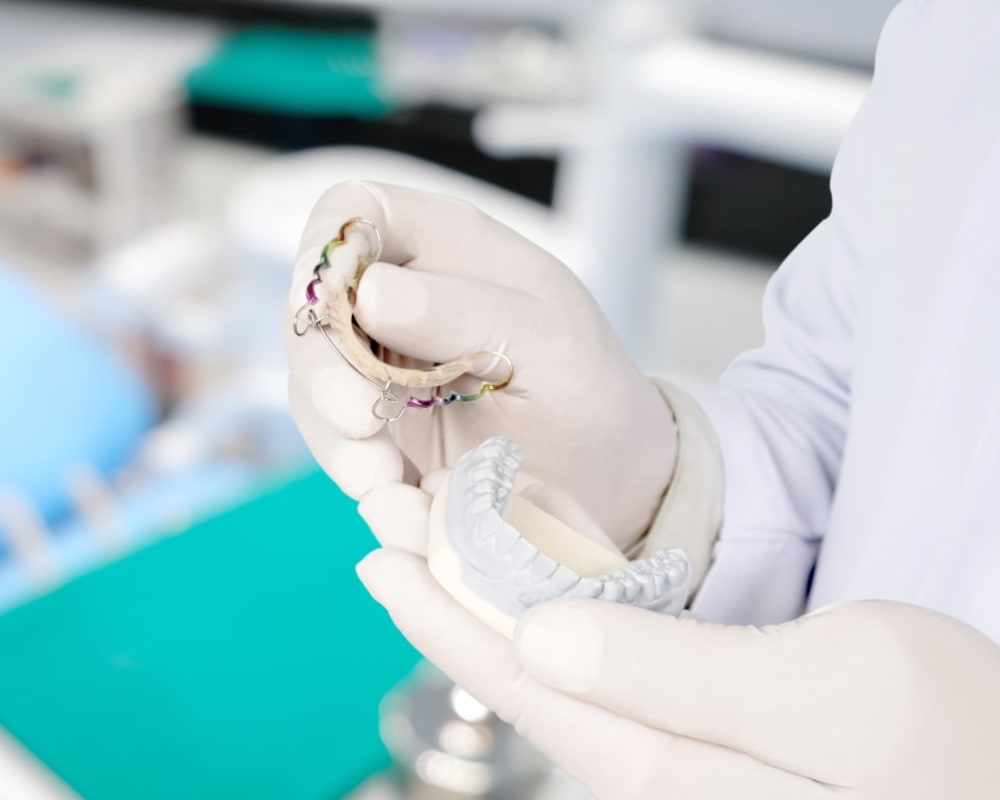 Someone is rinsing an orthodontic retainer at a sink.