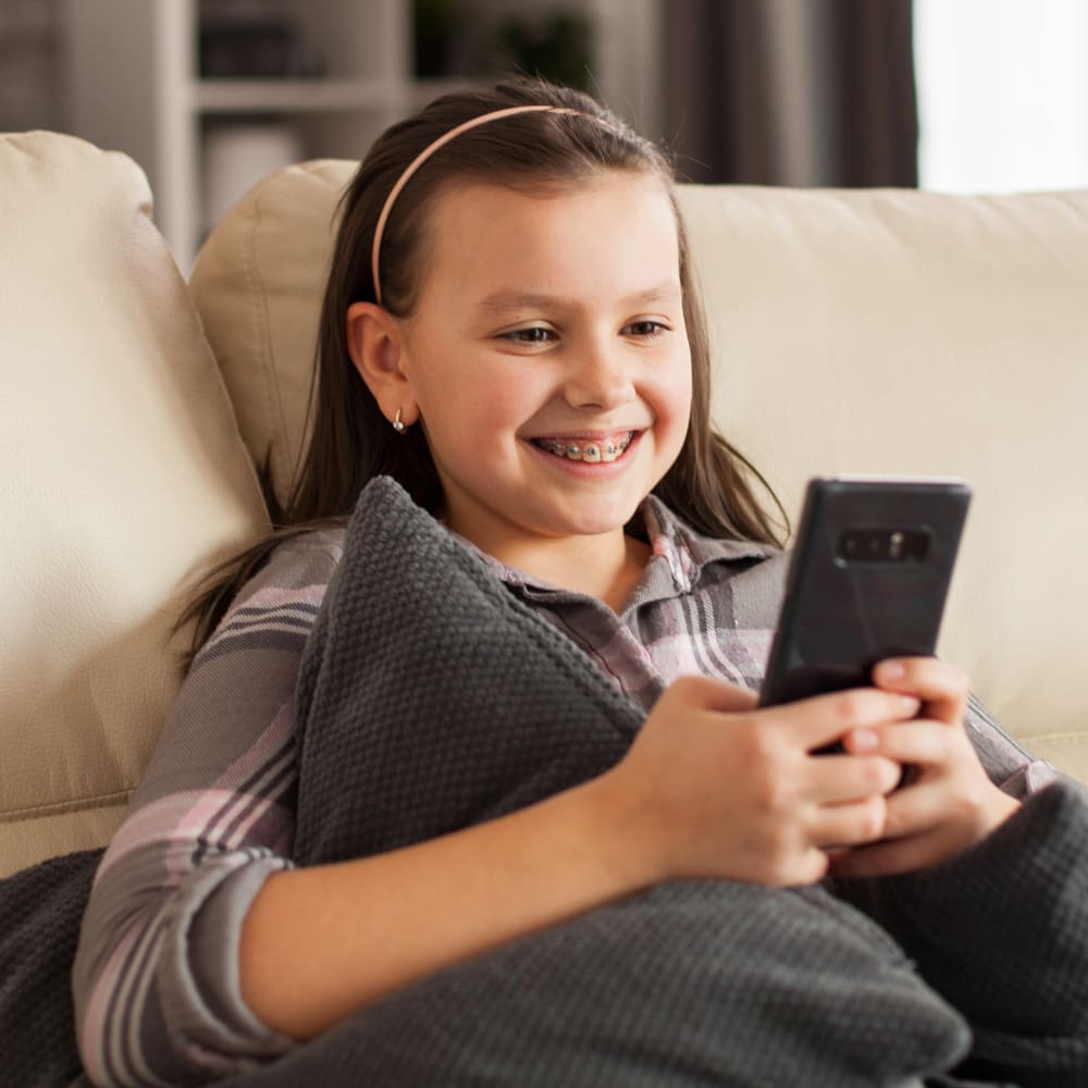 teen girl with teen braces smiling and looking at her mobile